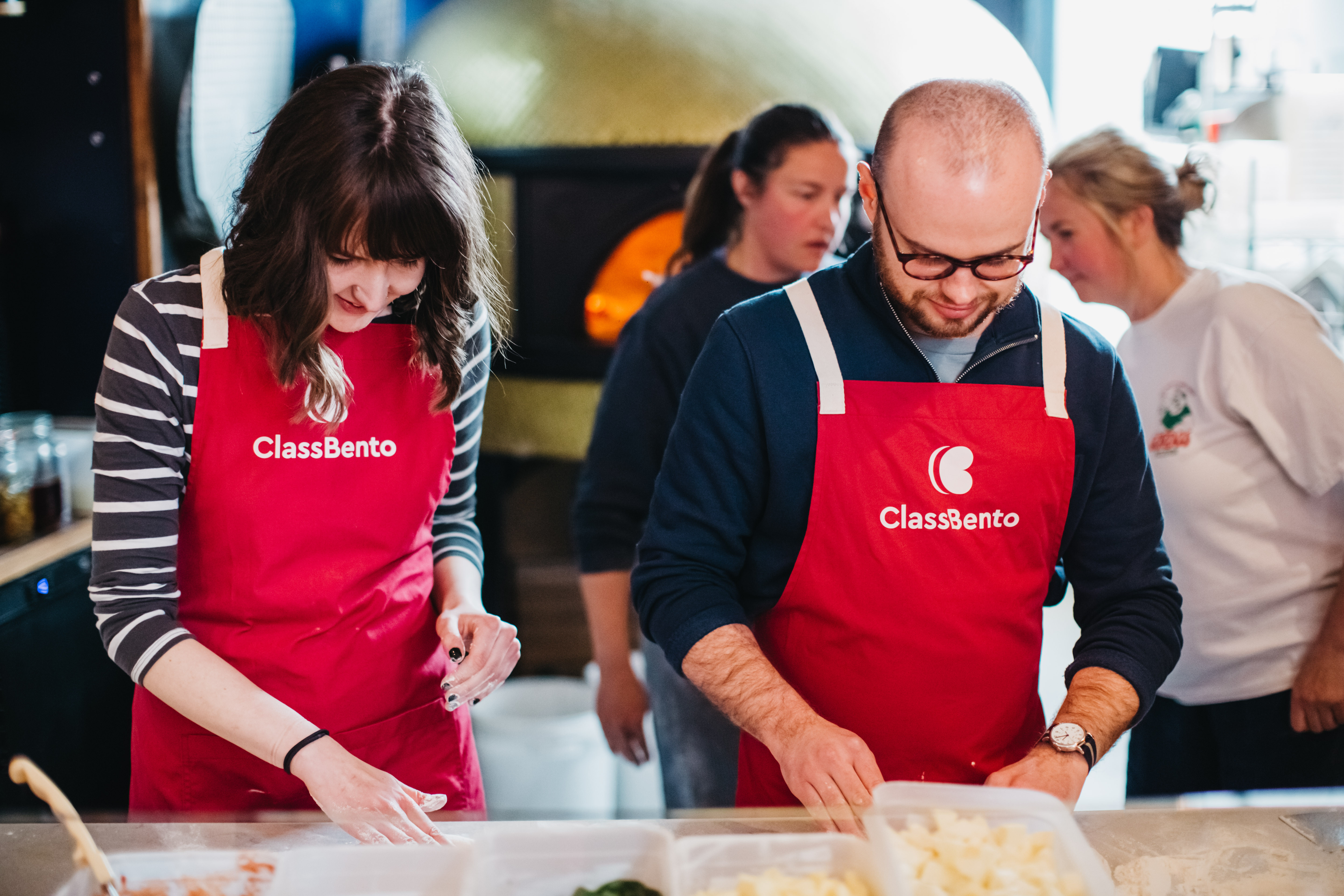 A couple learn how to make pizza together.